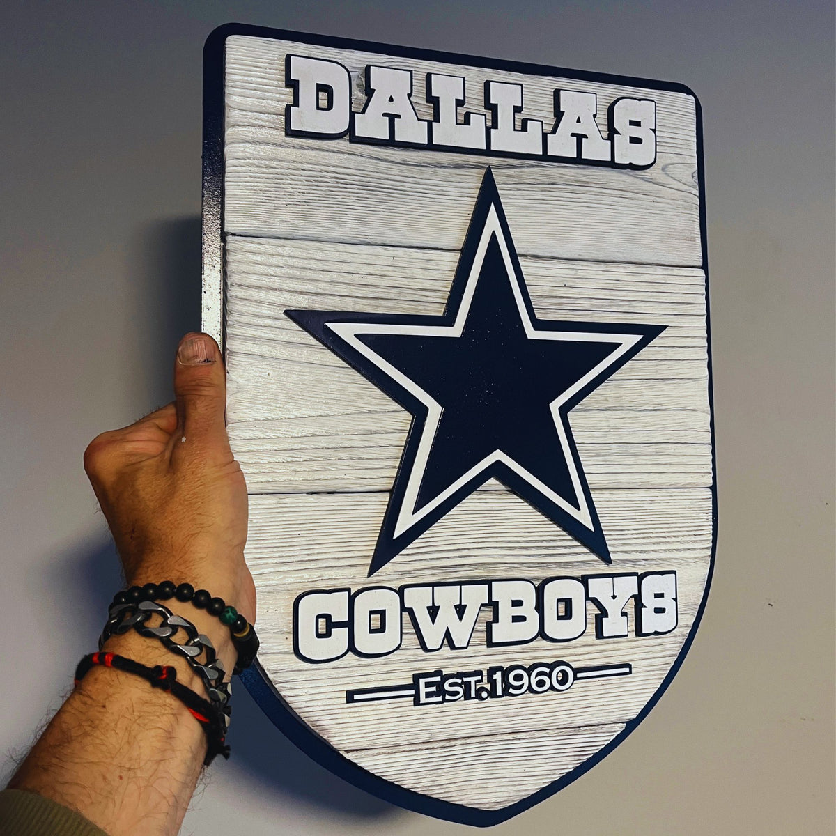 Wooden plaque with Dallas Cowboys logo and text on a plain background
